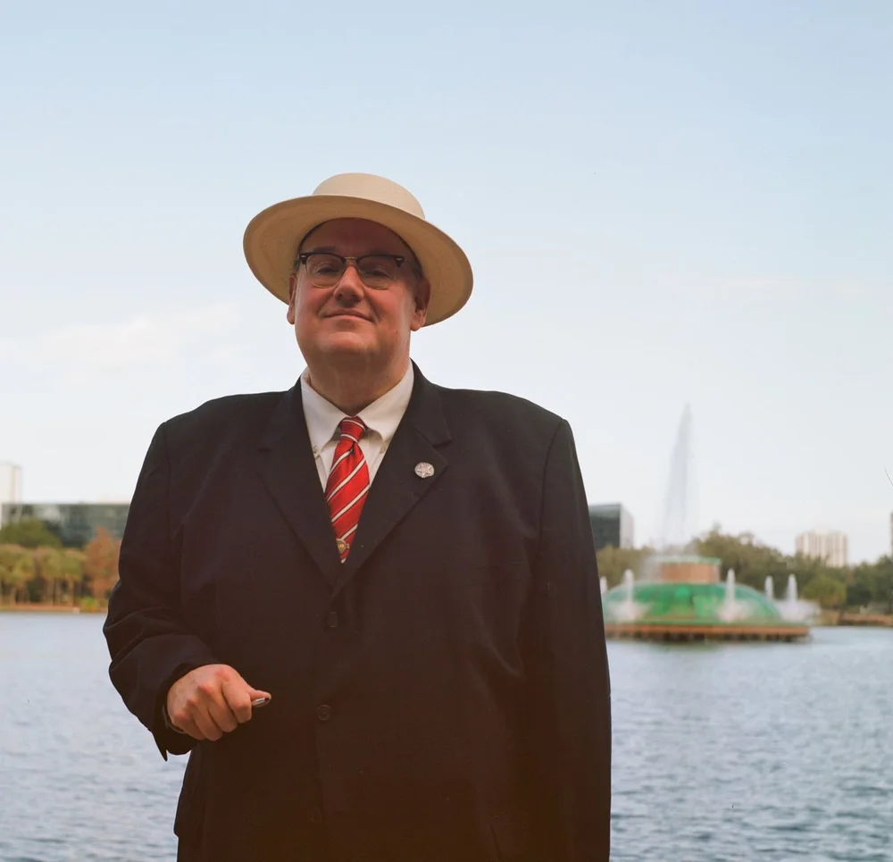man in suit standing in front of boat on water